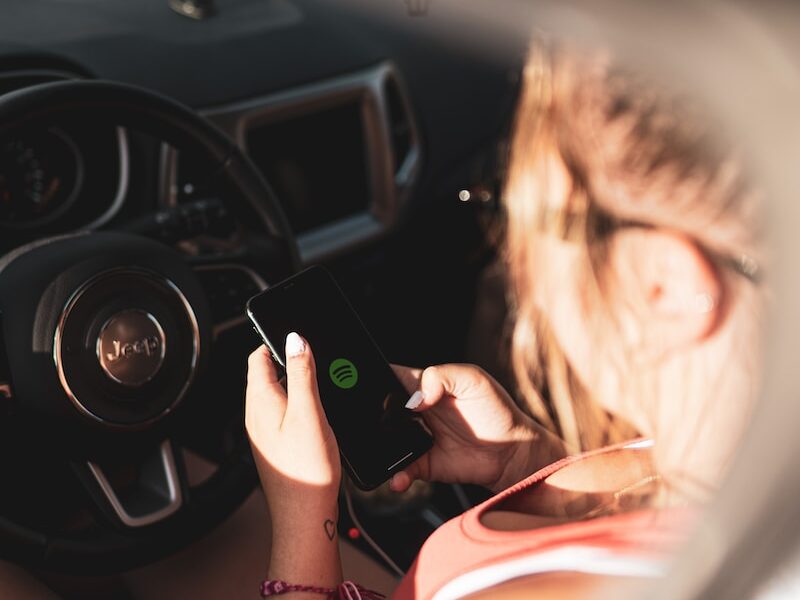 woman in pink tank top holding black smartphone