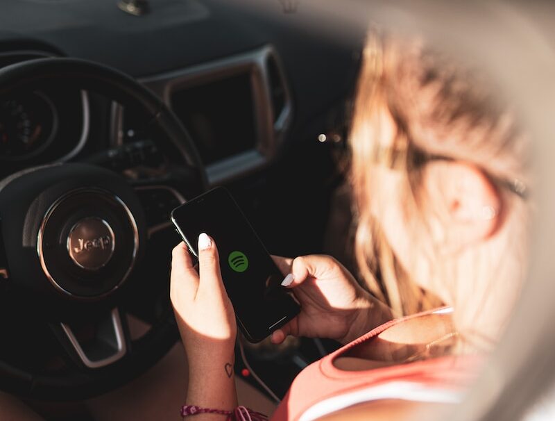 woman in pink tank top holding black smartphone