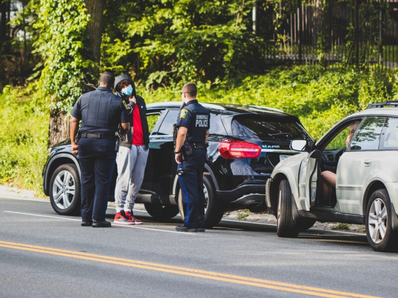 man in black t-shirt and black pants standing beside black suv during daytime