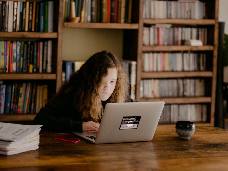 woman in black long sleeve shirt using macbook air on brown wooden table