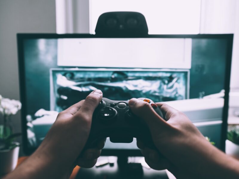 person holding game controller in-front of television