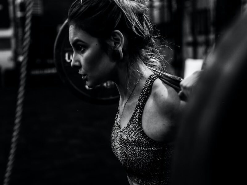 greyscale photo of woman in bralette inside room