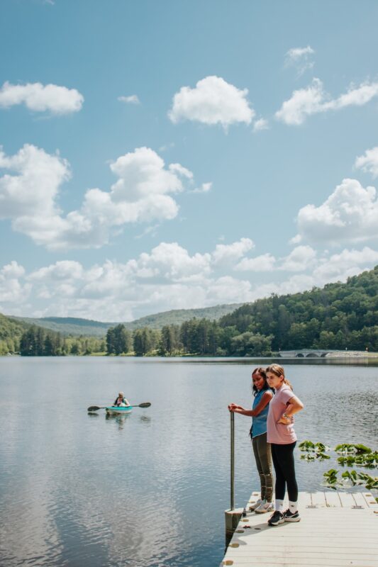 a couple of people standing on a pier next to a body of water