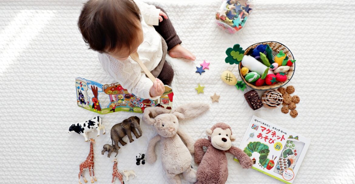 boy sitting on white cloth surrounded by toys