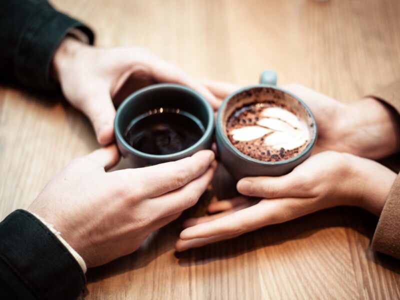 two person holding ceramic mugs with coffee